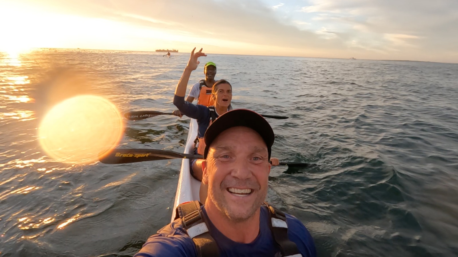 Three paddlers enjoying a tandem surfski outing at sunset