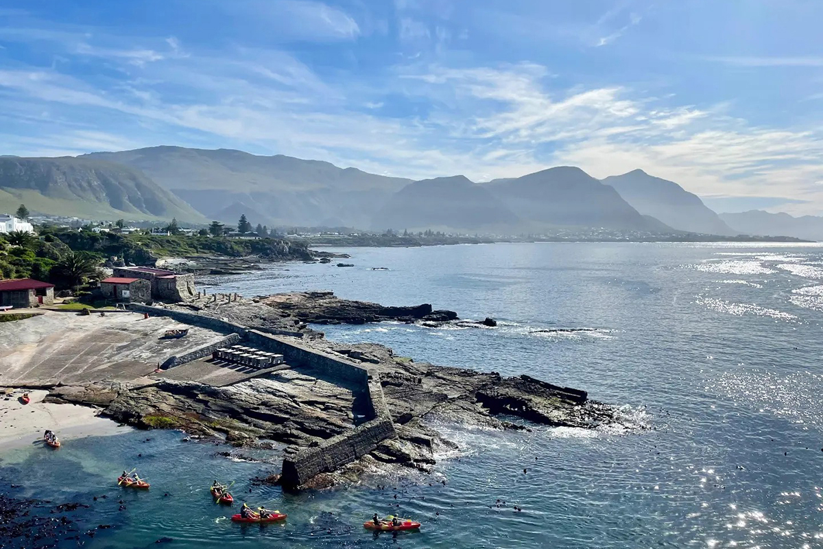 Aerial drone view of Walker Bay coastline with kayakers near Hermanus Old Harbour