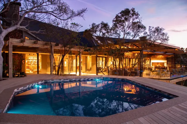Tented Lodge pool and lit main lodge at dusk, Botlierskop