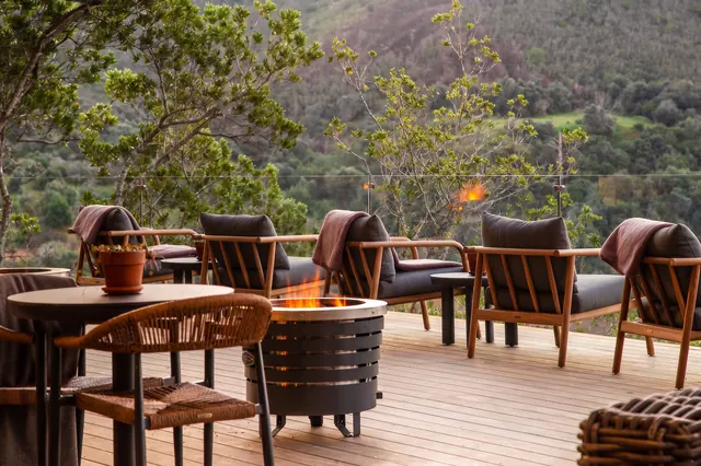 Outdoor restaurant deck with fire pit at Botlierskop Tented Lodge