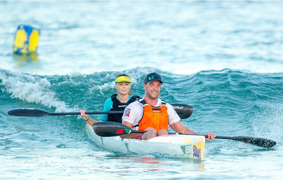 Tandem surfski paddlers gliding over a wave in False Bay